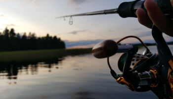 fishing,rod,wheel,closeup,,beautiful,lake,and,trees,reflections,in